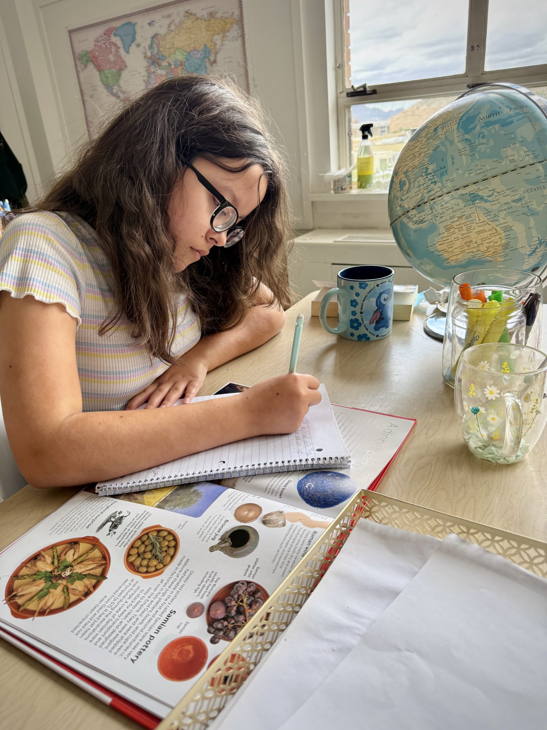 A Willows student writing beside books and classroom materials