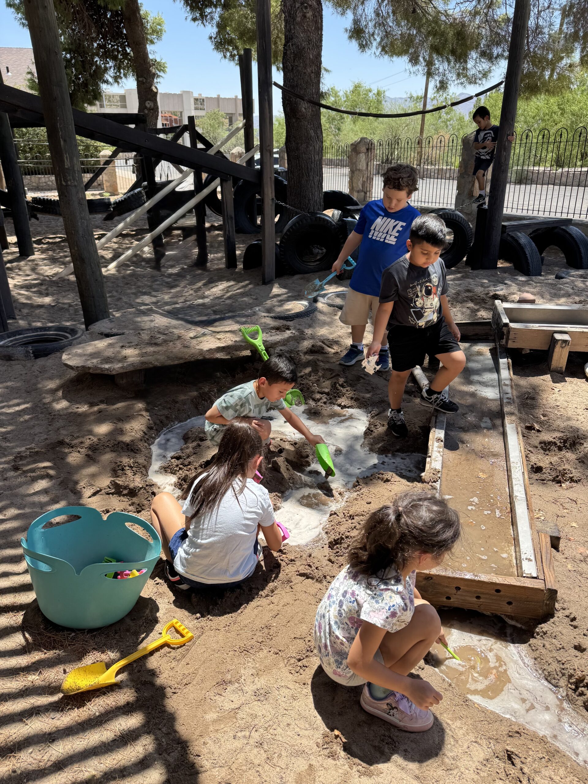 Children digging and investigating water and sand in the outdoor classroom