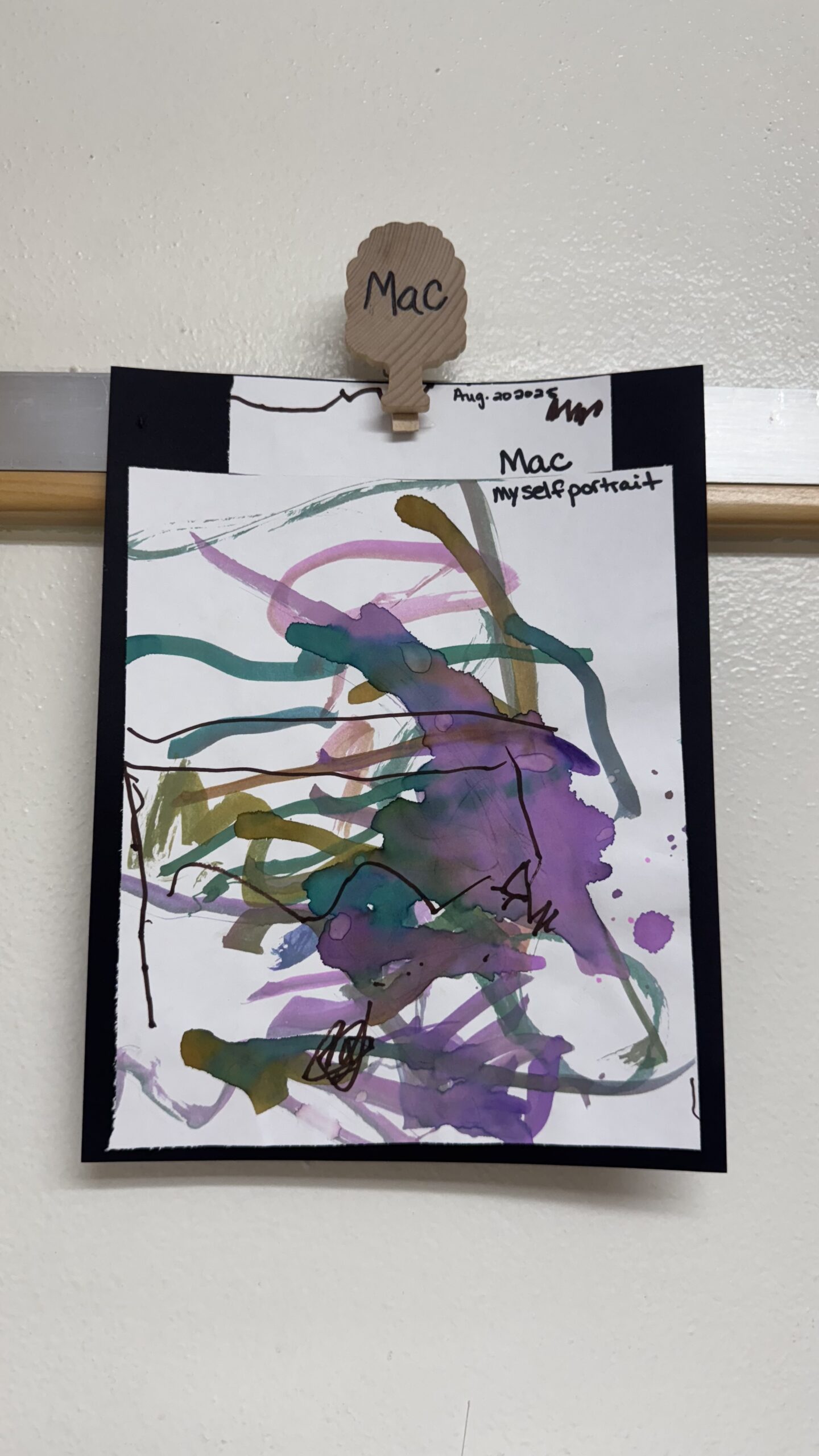 A child’s watercolor self-portrait displayed in the classroom.